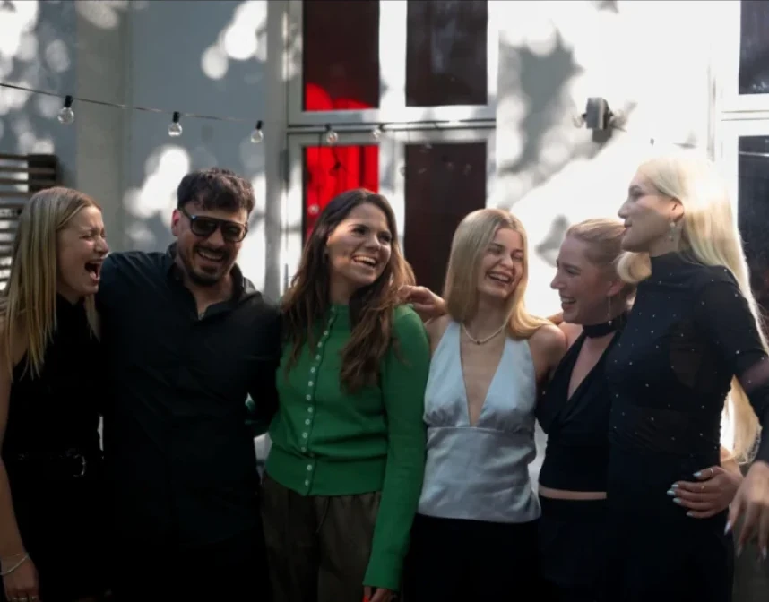 Sechs Mitglieder der Community lachen bei einem Sommer-Event zusammen